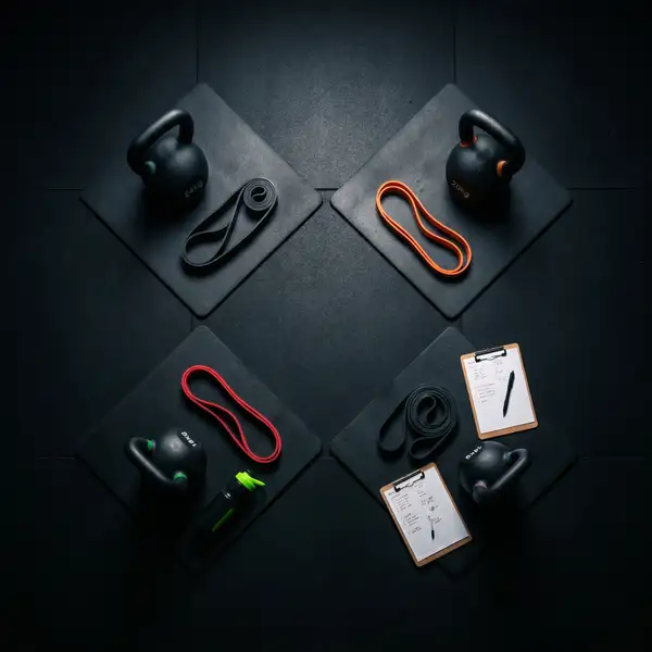 Top-down overhead view of a Small Group PT layout at CXHW showing four kitted mats, kettlebells, resistance bands, and a clipboard